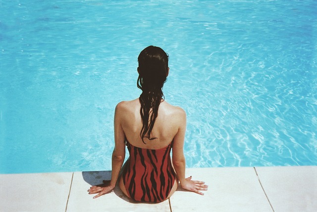 žena sedící na okraji bazénu